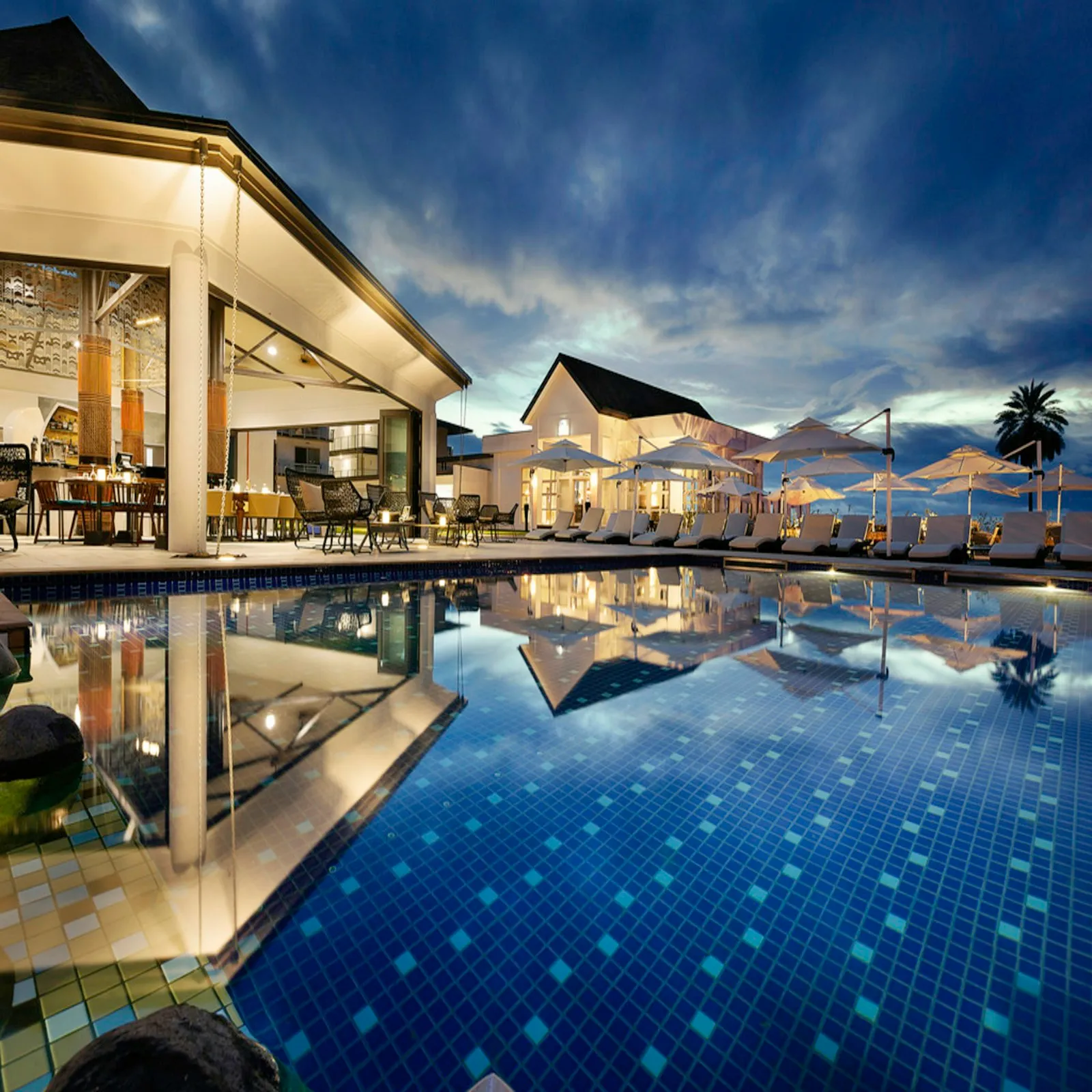 Resort pool reflecting tropical architecture and the evening sky